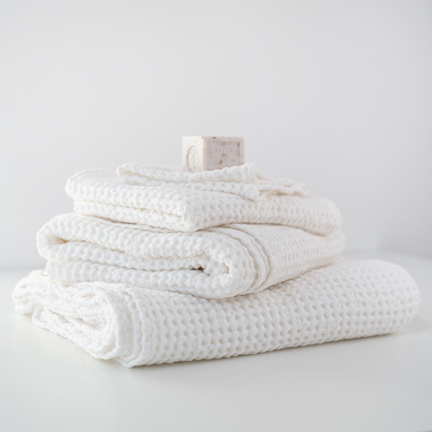 1. Stack of white honeycomb waffle towels with a soap bar on top, showcasing texture and volume