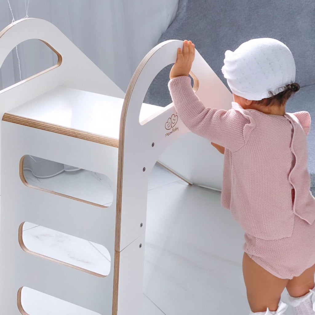 1. Child climbing a white wooden slide in a bright room