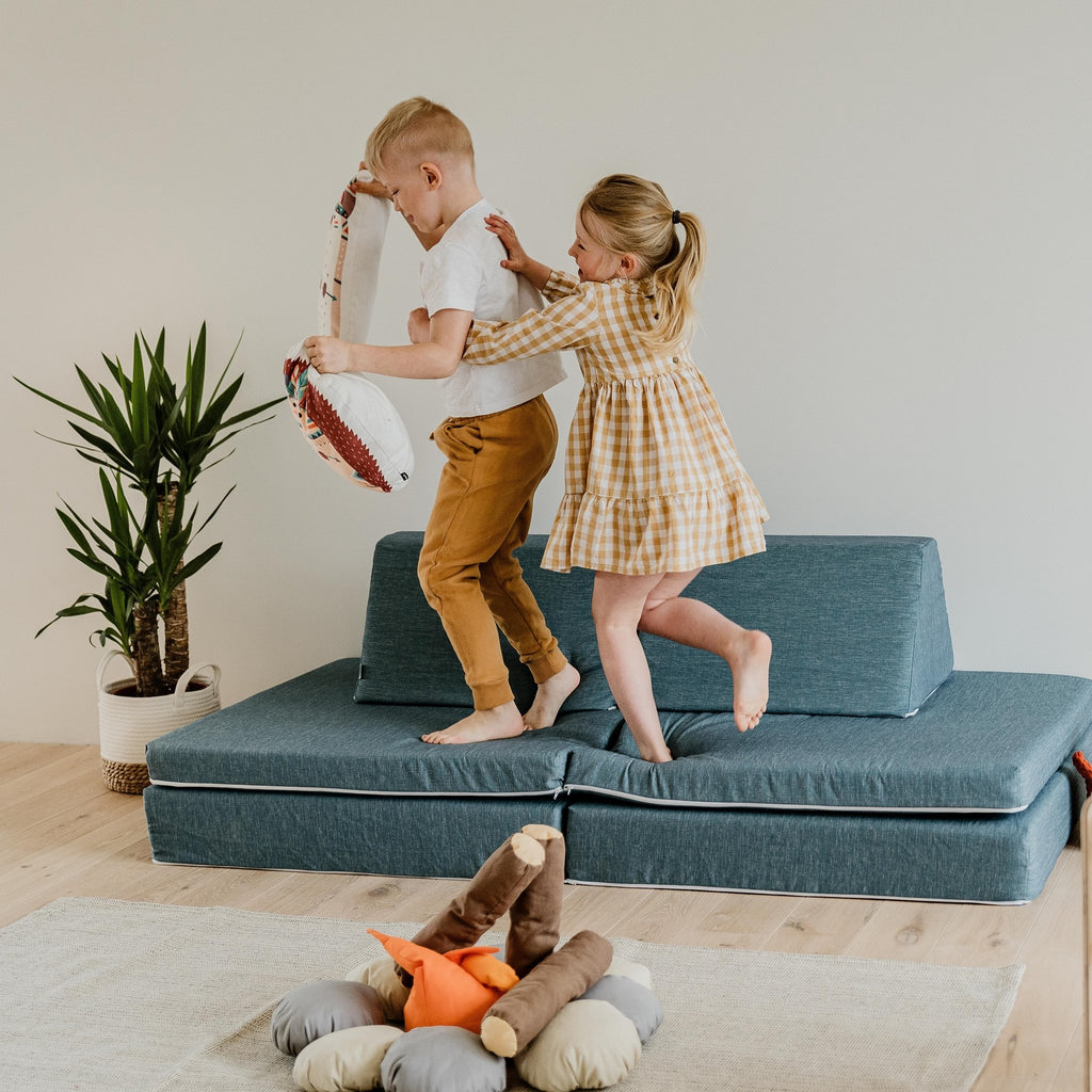5. Two children playing on turquoise Monboxy play mattress sofa in a bright room with a plant
