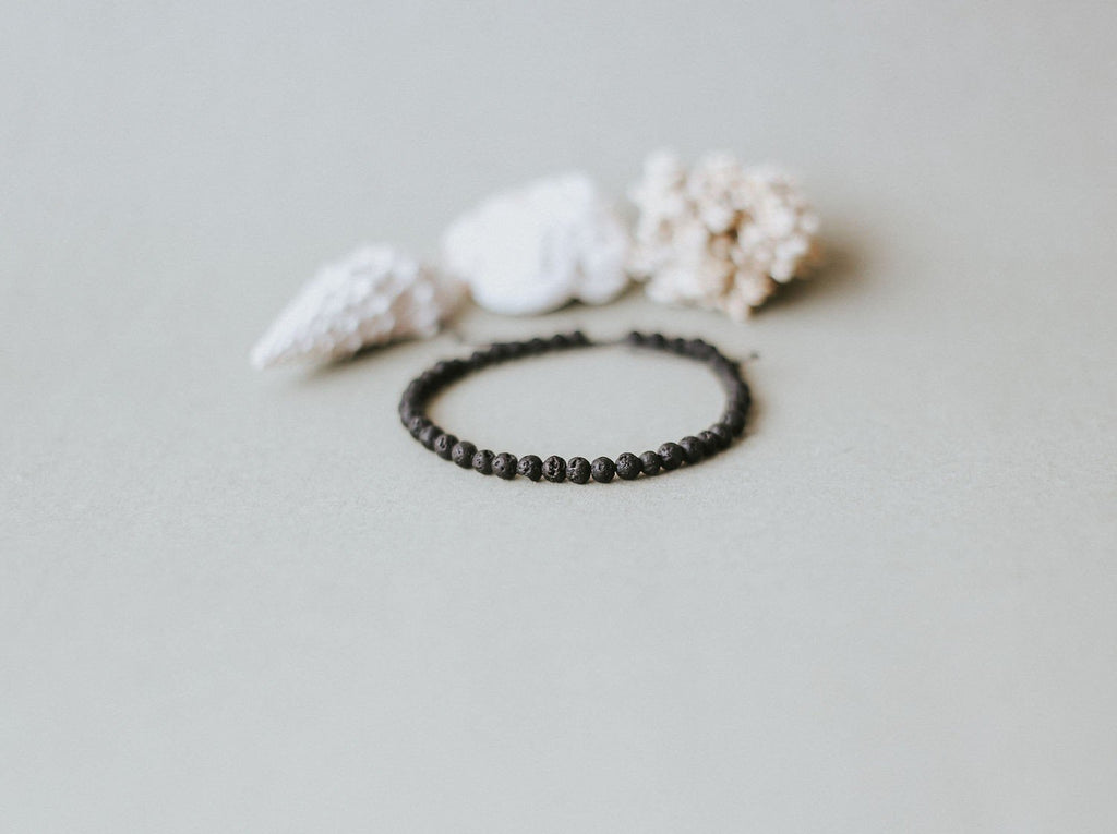 3. Flat lay of Canary Lava's 4mm minimalist lava stone bracelet with natural elements, highlighting volcanic beads and adjustable design