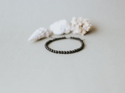 3. Flat lay of Canary Lava's 4mm minimalist lava stone bracelet with natural elements, highlighting volcanic beads and adjustable design