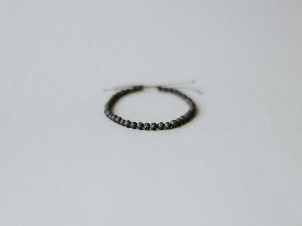2. Studio shot of Canary Lava's adjustable 4mm minimalist lava stone bracelet, featuring polished volcanic stones and black kevlar string