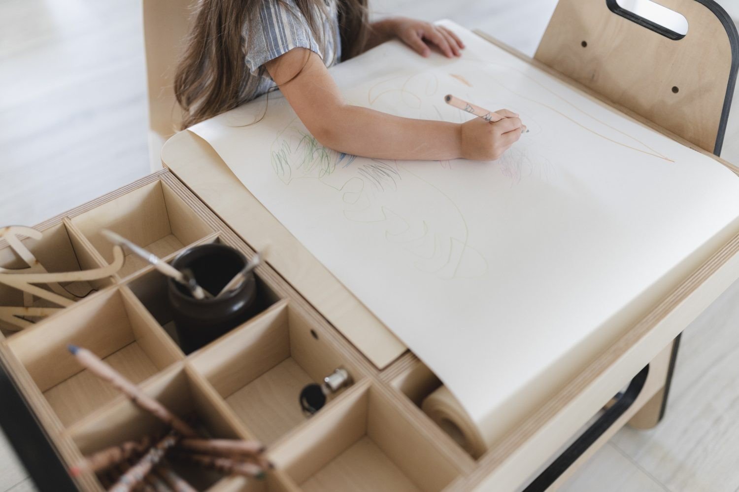 3. Close-up of child drawing on paper at Montessori table