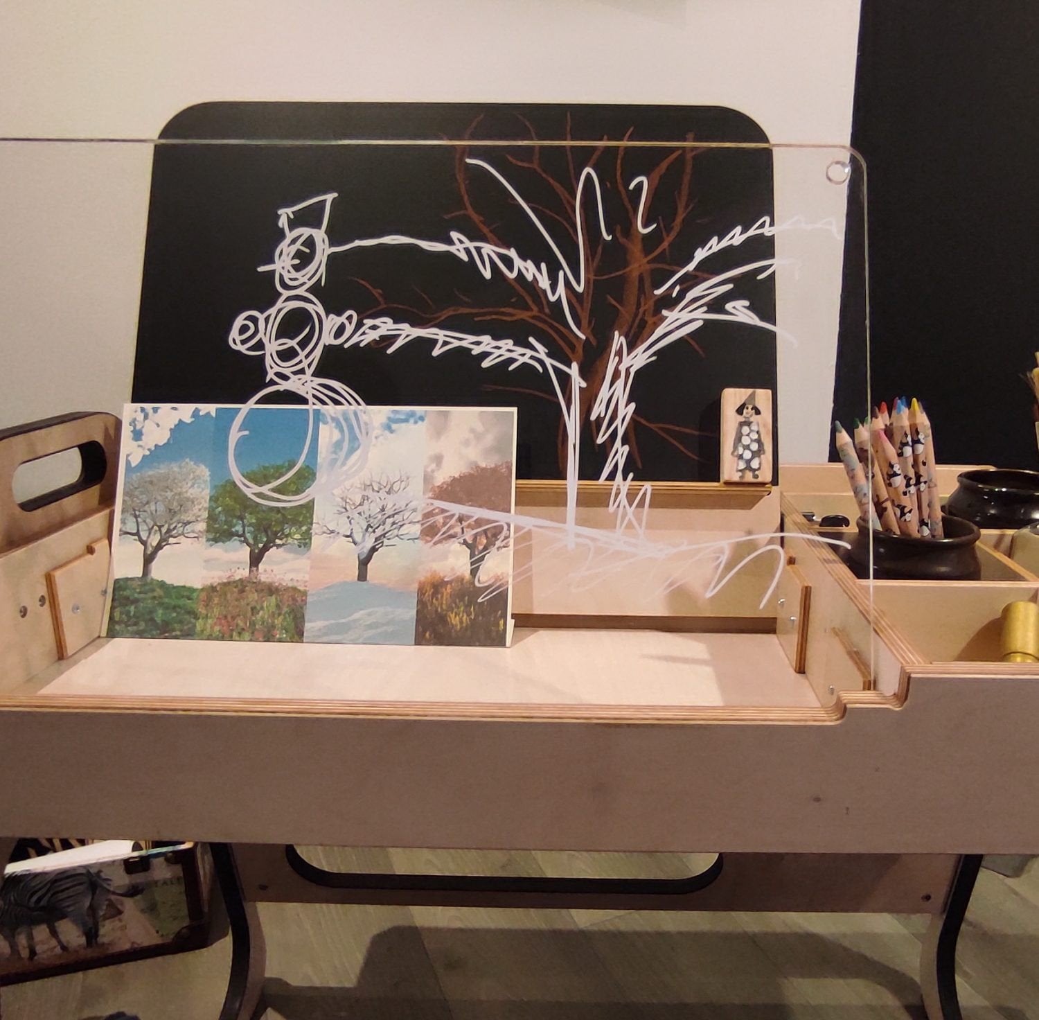 2. Children's table with transparent acrylic board and art supplies, showcasing creative drawing space in a home setting.