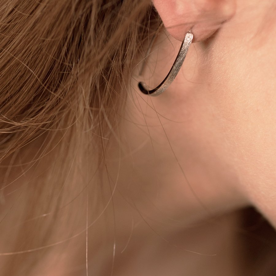 1. Close-up of MyaMoon Small Arch Earring worn by a woman, showcasing Nordic minimalist design in 925 silver with rhodium plating