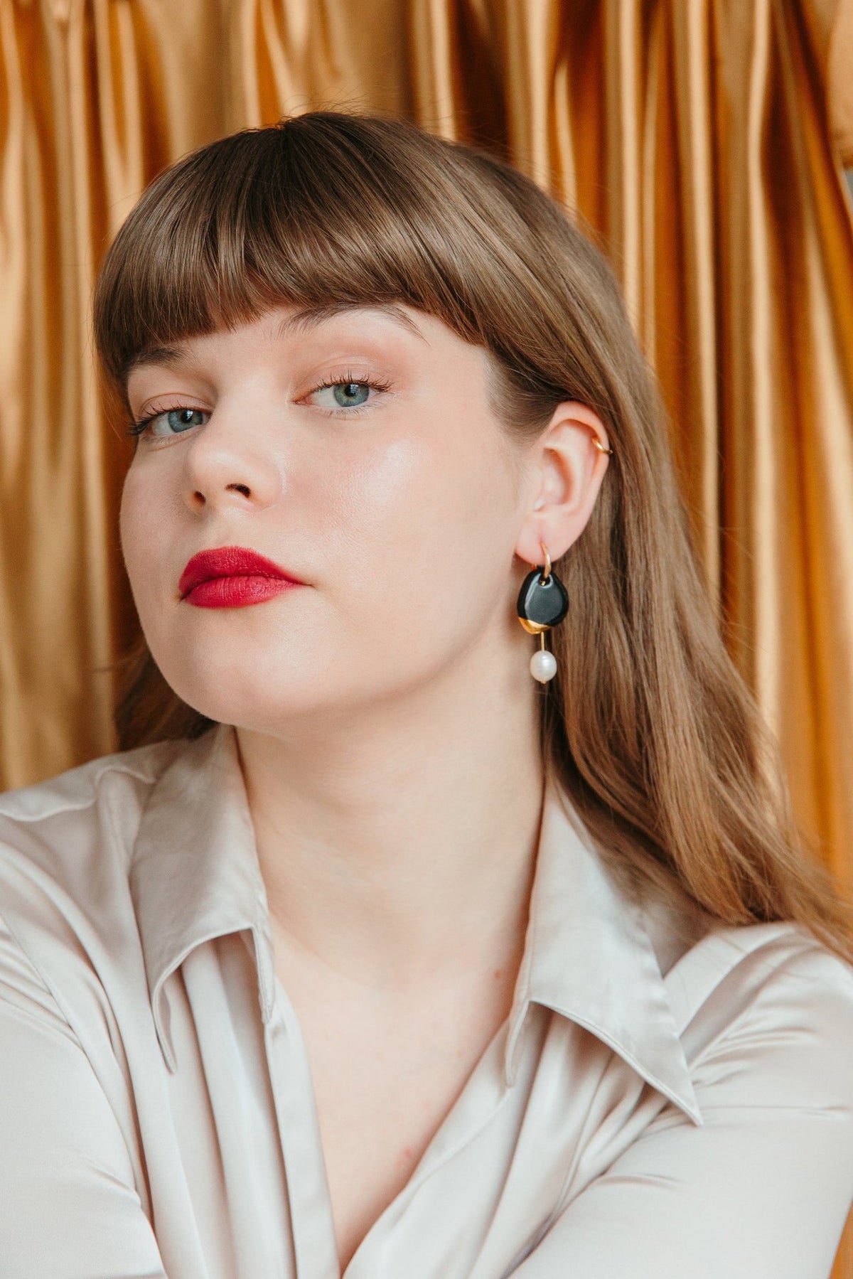 1. Woman wearing Rozenthal Arp Pearl And Porcelain Earrings in dark green, showcasing elegant design with freshwater pearls and gold-plated hoops