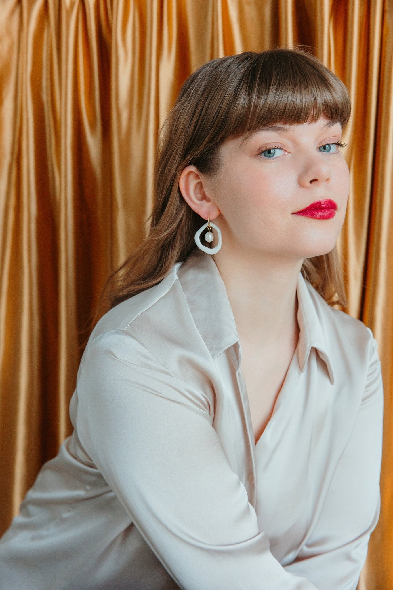2. Woman styled with Rozenthal Arp Pearl and Porcelain Hoops in white, highlighting biomorphic abstractionism and luxury