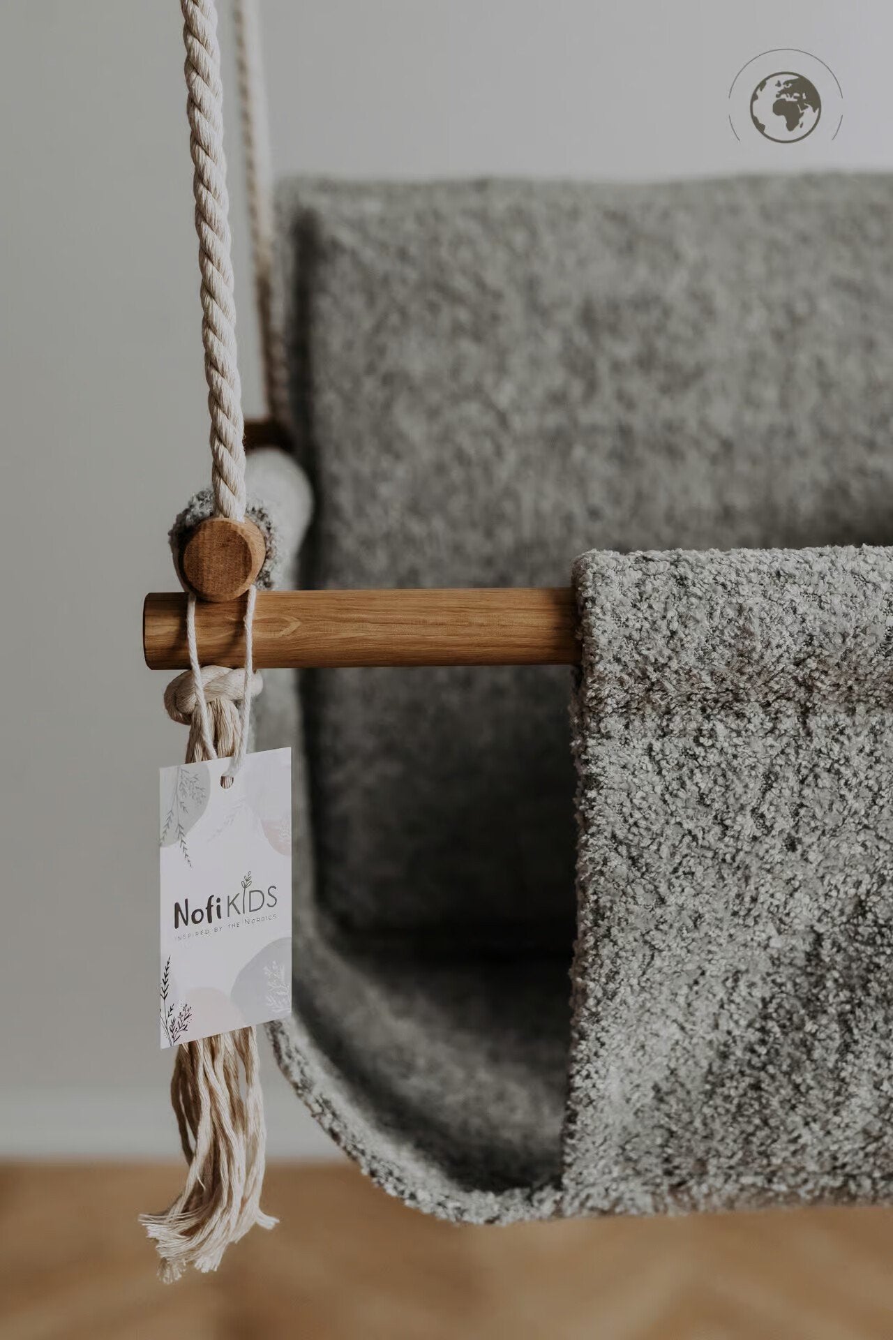 3. Close-up of Nofi KIDS tag on grey bouclé fabric baby swing with oak wood pole