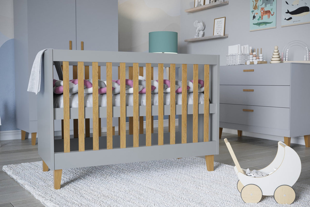 1. Close-up of grey baby cot with oak slats in stylish nursery, featuring toys and decor