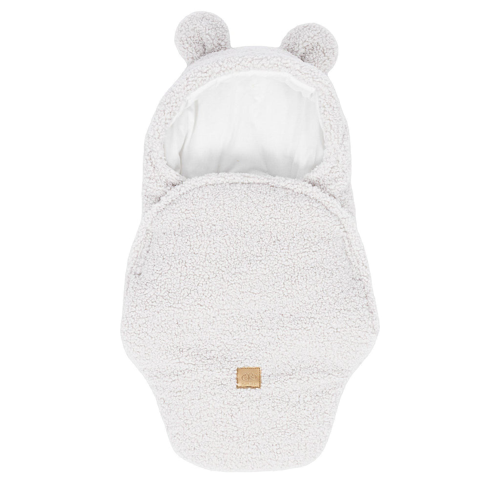 1. Off-white baby swaddle with bear ears made of boucle fabric, featuring a cotton inner layer and velcro closure, shown in a flat lay view