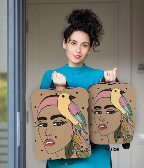 3. Woman holding Garbanota BACKPACK TINA in L and M sizes, featuring colorful artwork and bird design