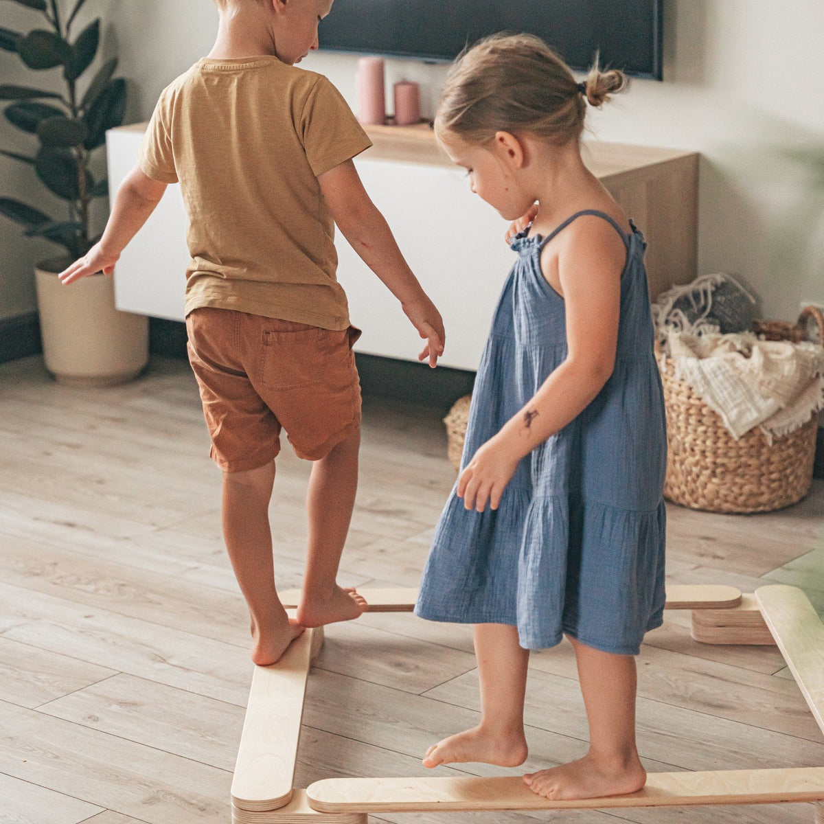 2. Two children playing on wooden leg&go balance beams in a living room setting