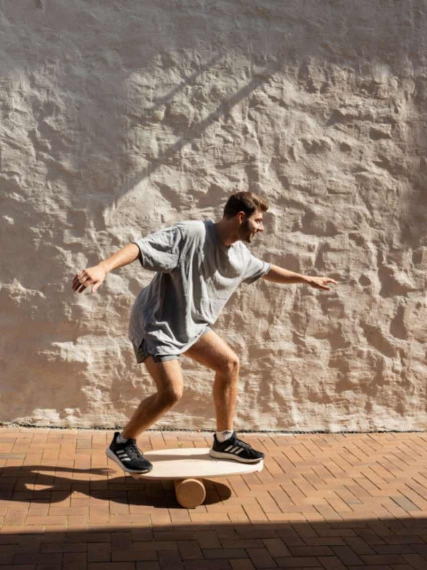 1. Man balancing on leg&go balance board with cork roller outdoors, wearing casual athletic wear