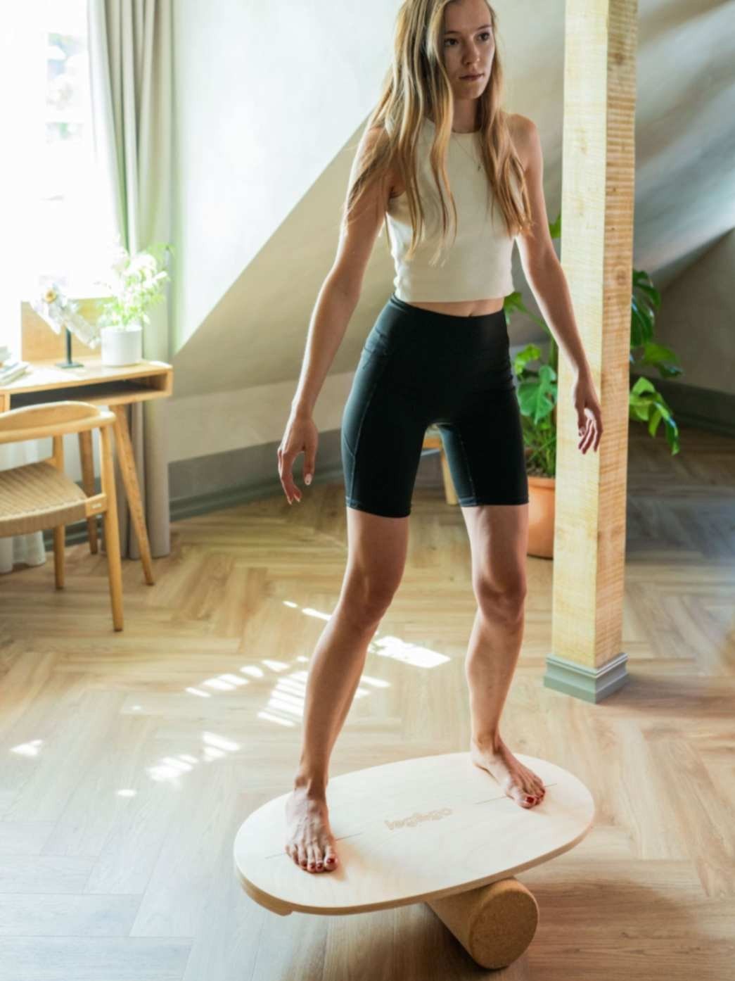 1. Woman standing on leg&go balance board with cork roller in a bright, modern living space