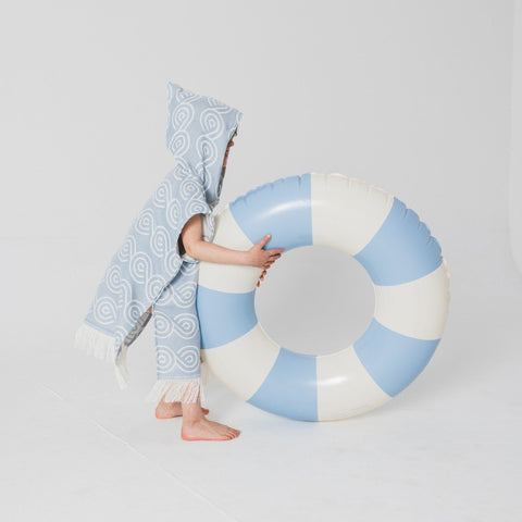 5. Child in light blue Patulove bamboo bath poncho with hood, holding large blue and white inflatable ring