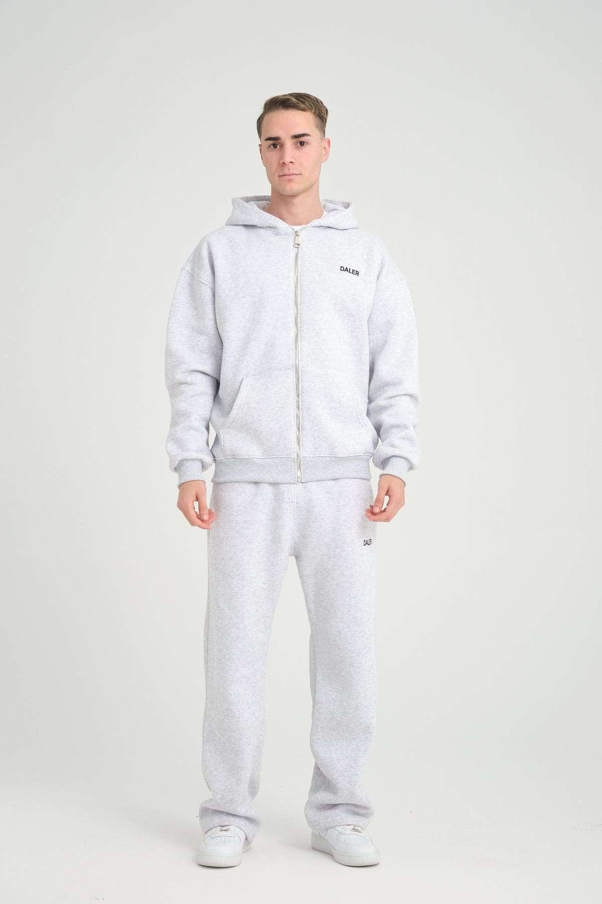 1. Man wearing grey melange jogger pants and matching hoodie, standing in studio setting