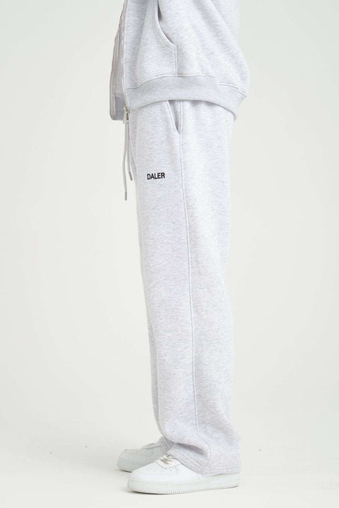 2. Side view of grey melange jogger pants with DALER logo, paired with white sneakers