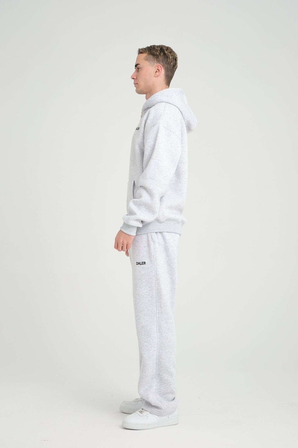 2. Side view of man in grey melange DalerClo hoodie and pants, standing in studio