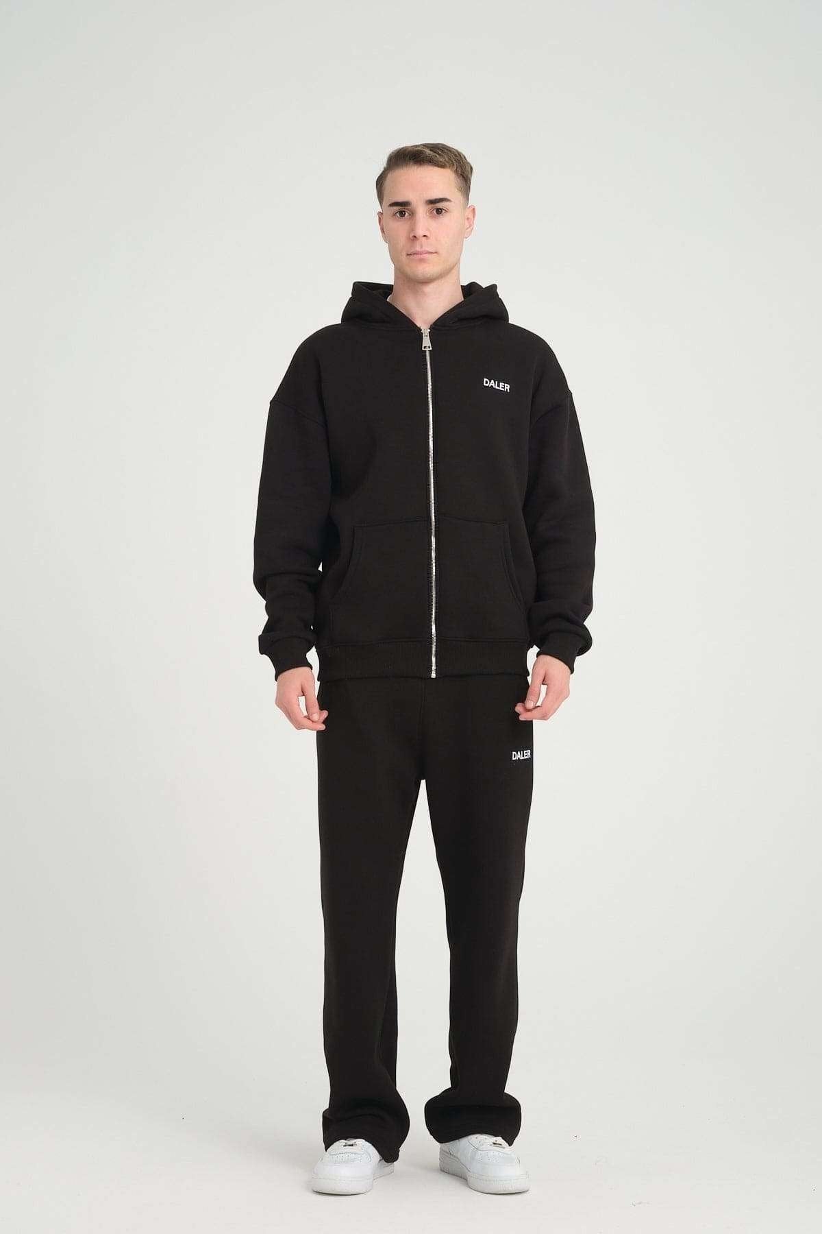 4. Man in black jogger pants and hoodie with DALER logo, facing forward in studio