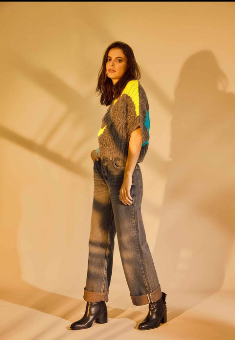 1. Woman in colorful sweater and jeans wearing black leather ankle boots with block heel in warm indoor setting