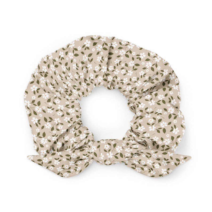 1. Beige scrunchie with floral pattern and bow detail made from recycled polyester, shown in a flat lay on a white background