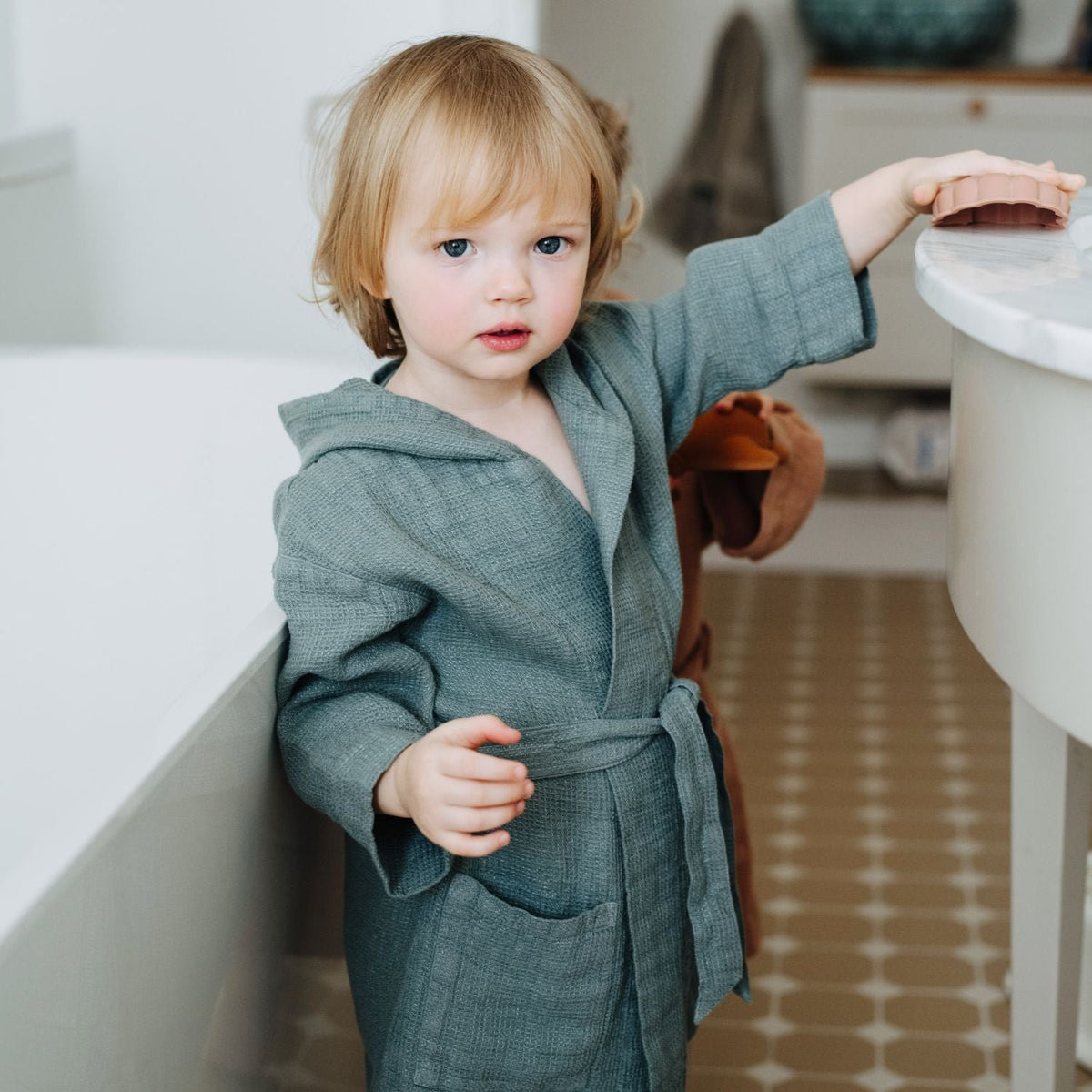 1. Child wearing blue fog linen bathrobe with hood in bathroom setting