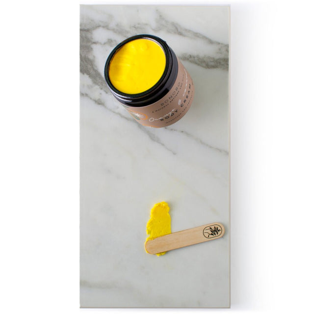 4. Close-up of BONOBO Orange & Carrot Body Cream with vibrant yellow texture and wooden spatula on marble surface