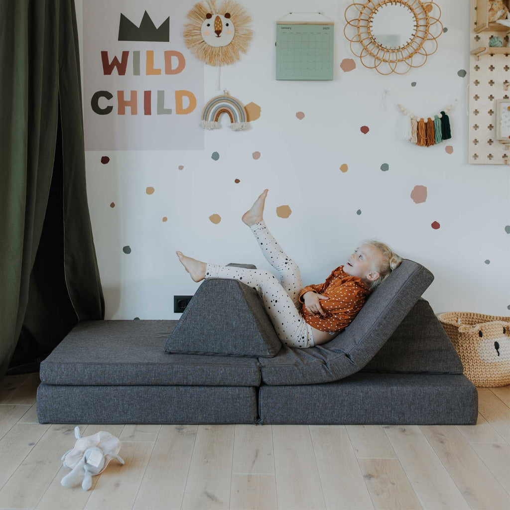 6. Child lounging on Monboxy dark brown play mattress set configured as a recliner in a playroom