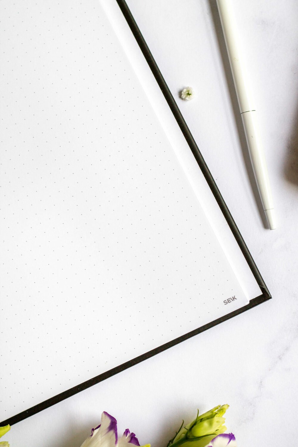 4. Open SEIK Premium Dream Plan Do Notebook showing dot-grid pages with pen and flowers in lifestyle setting