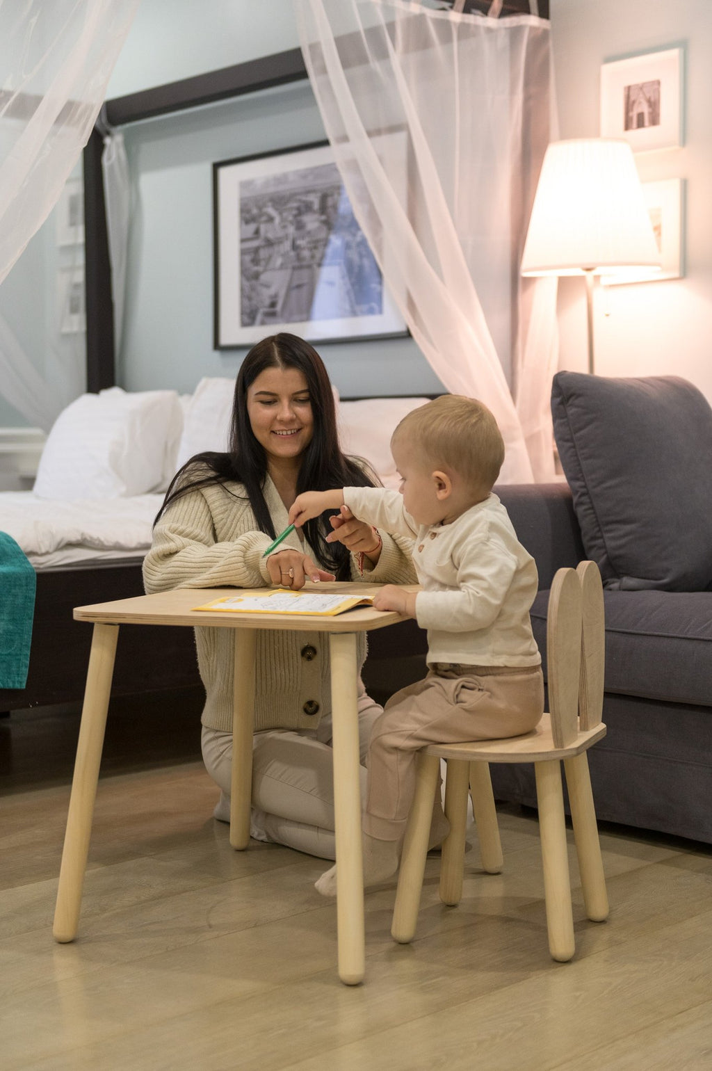 6. Woman and child using a natural wood bunny-themed table and chair set in a cozy bedroom setting