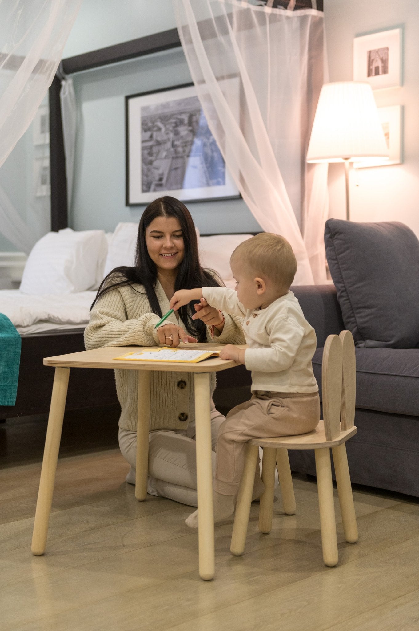 6. Woman and child using a natural wood bunny-themed table and chair set in a cozy bedroom setting