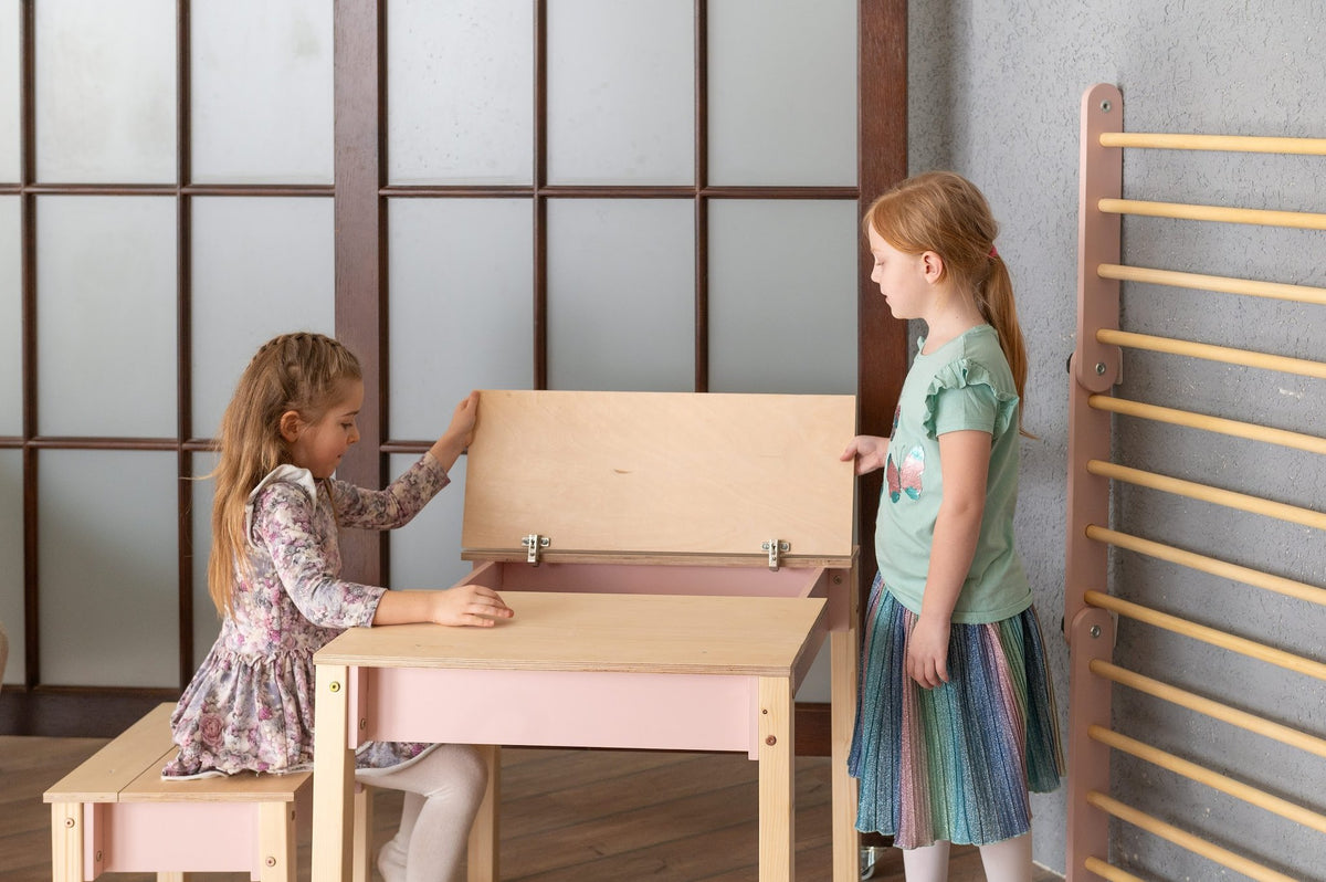 1. Two girls interacting with smart storage table and chair set in a playroom, one sitting and one standing