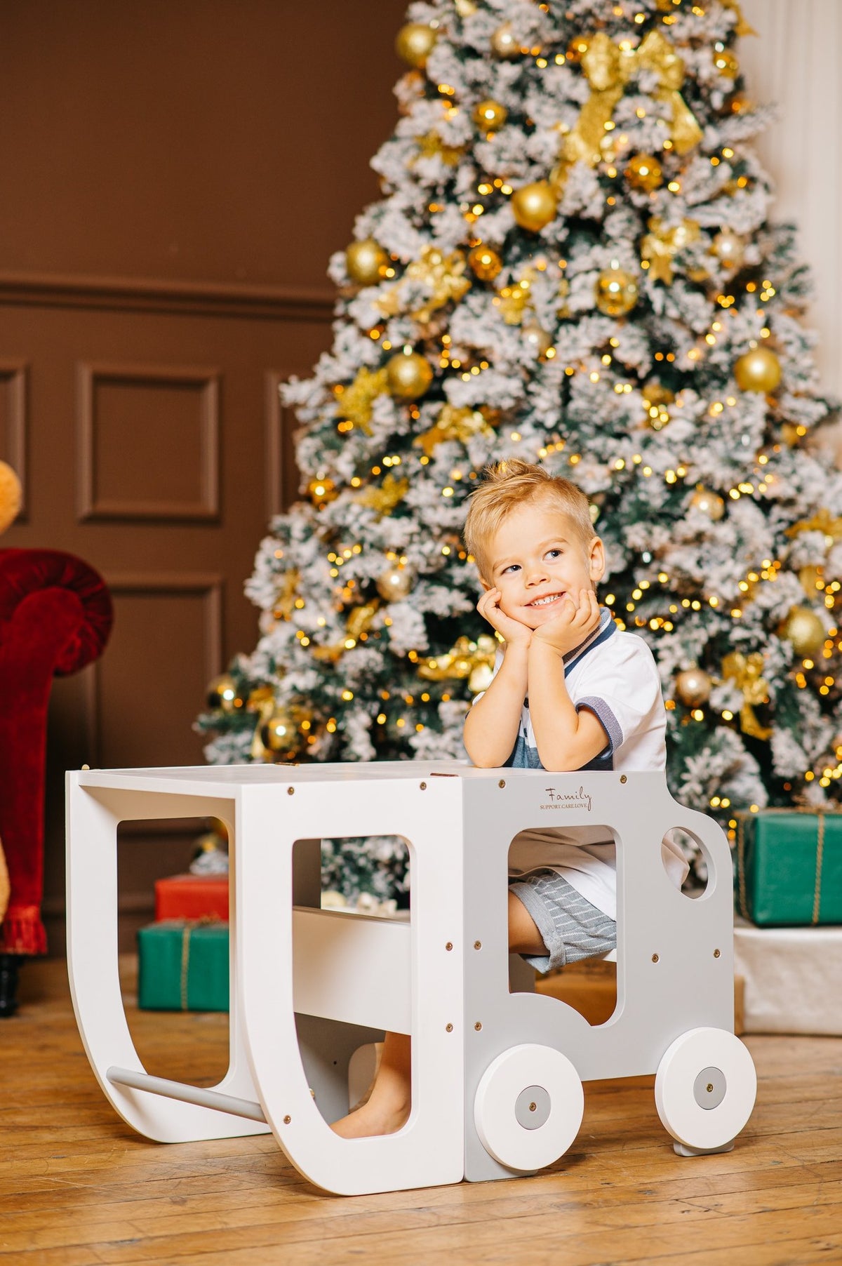 1. Child sitting at white Montessori learning table with Christmas tree in background