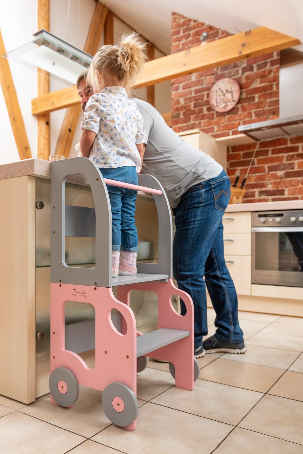 1. Child and adult using pink and grey Montessori kitchen step stool at kitchen counter