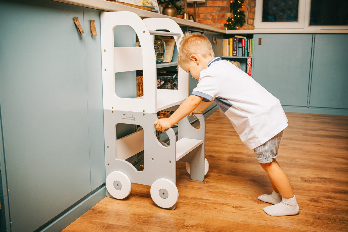 1. Child pushing grey and white Montessori kitchen step stool in kitchen