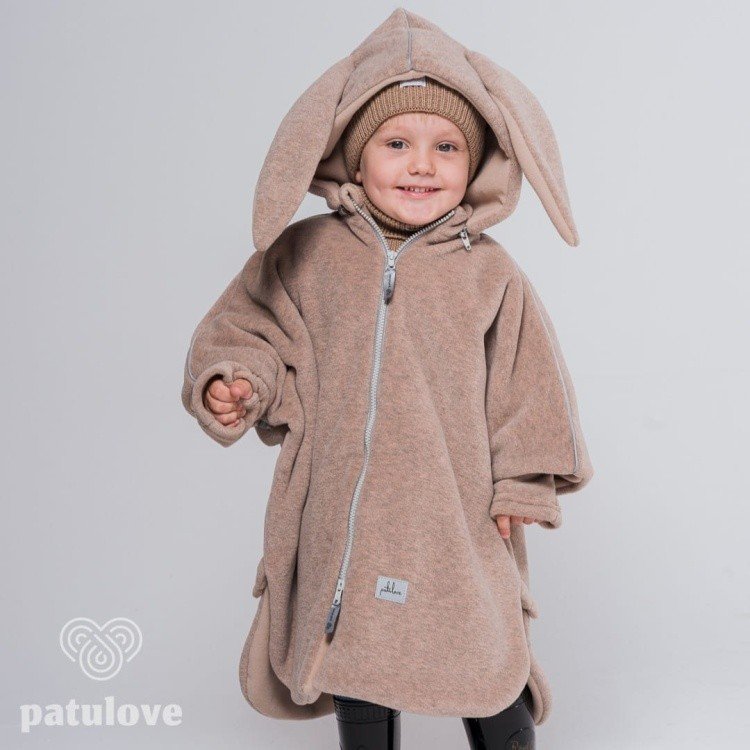 1. Child wearing Patulove beige bunny car poncho with hood and zipper, smiling in studio setting