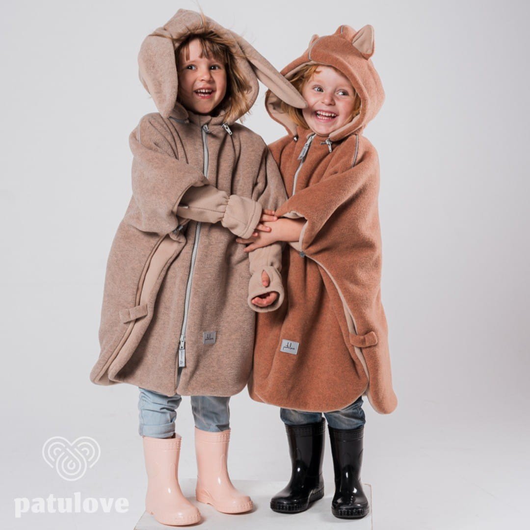 7. Two children wearing Patulove car ponchos, one fox-themed and one bunny-themed, smiling and holding hands