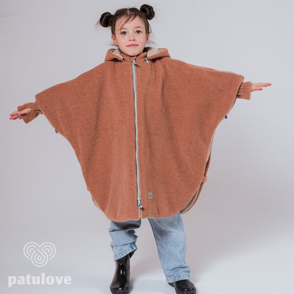 4. Girl in Patulove fox car poncho with arms outstretched, wearing jeans and black boots in studio
