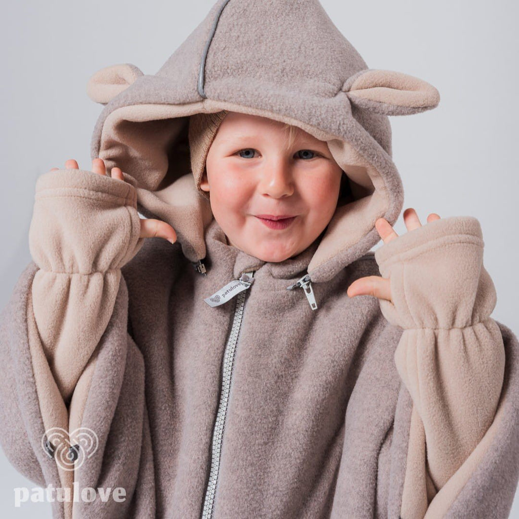 1. Child wearing Patulove lamb beige car poncho with hood and ear details, smiling in studio setting