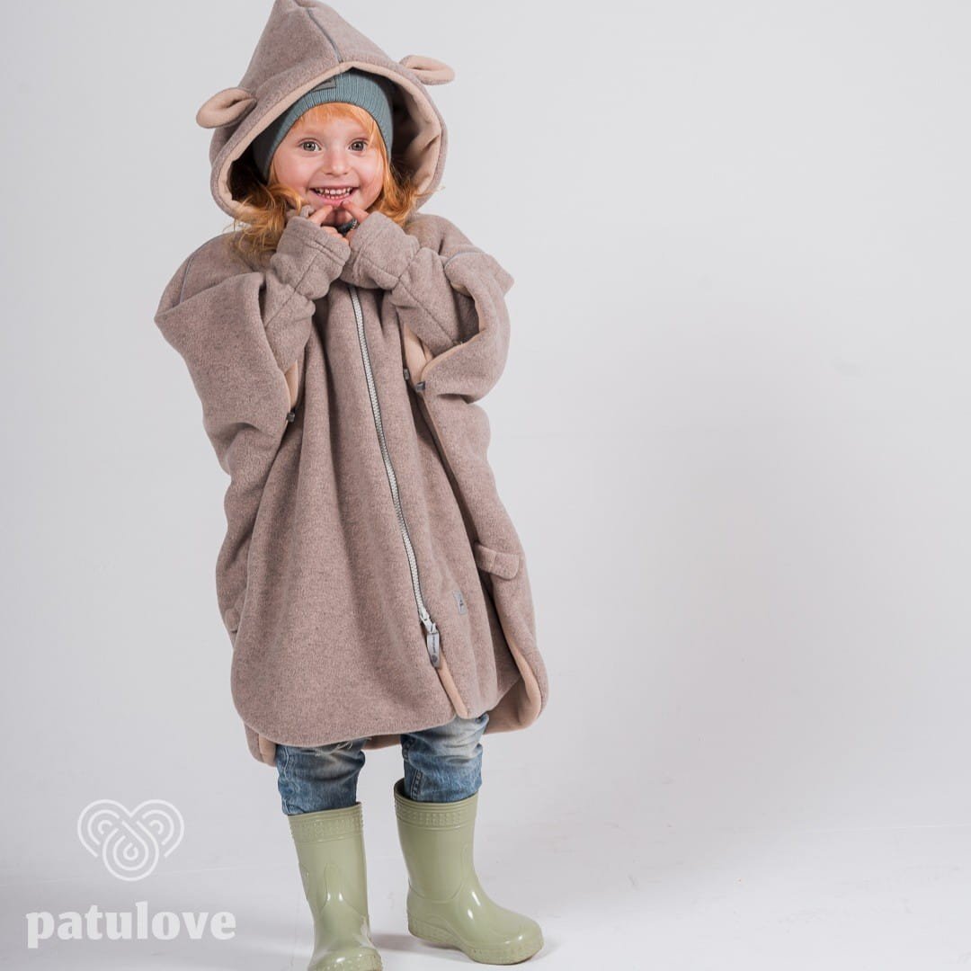 1. Girl wearing Patulove lamb beige car poncho with hood and green boots, smiling in studio