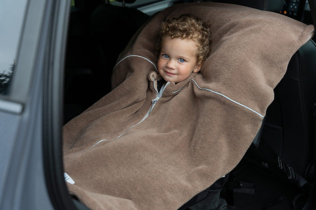 8. Child in car seat covered with brown Patulove car poncho, smiling
