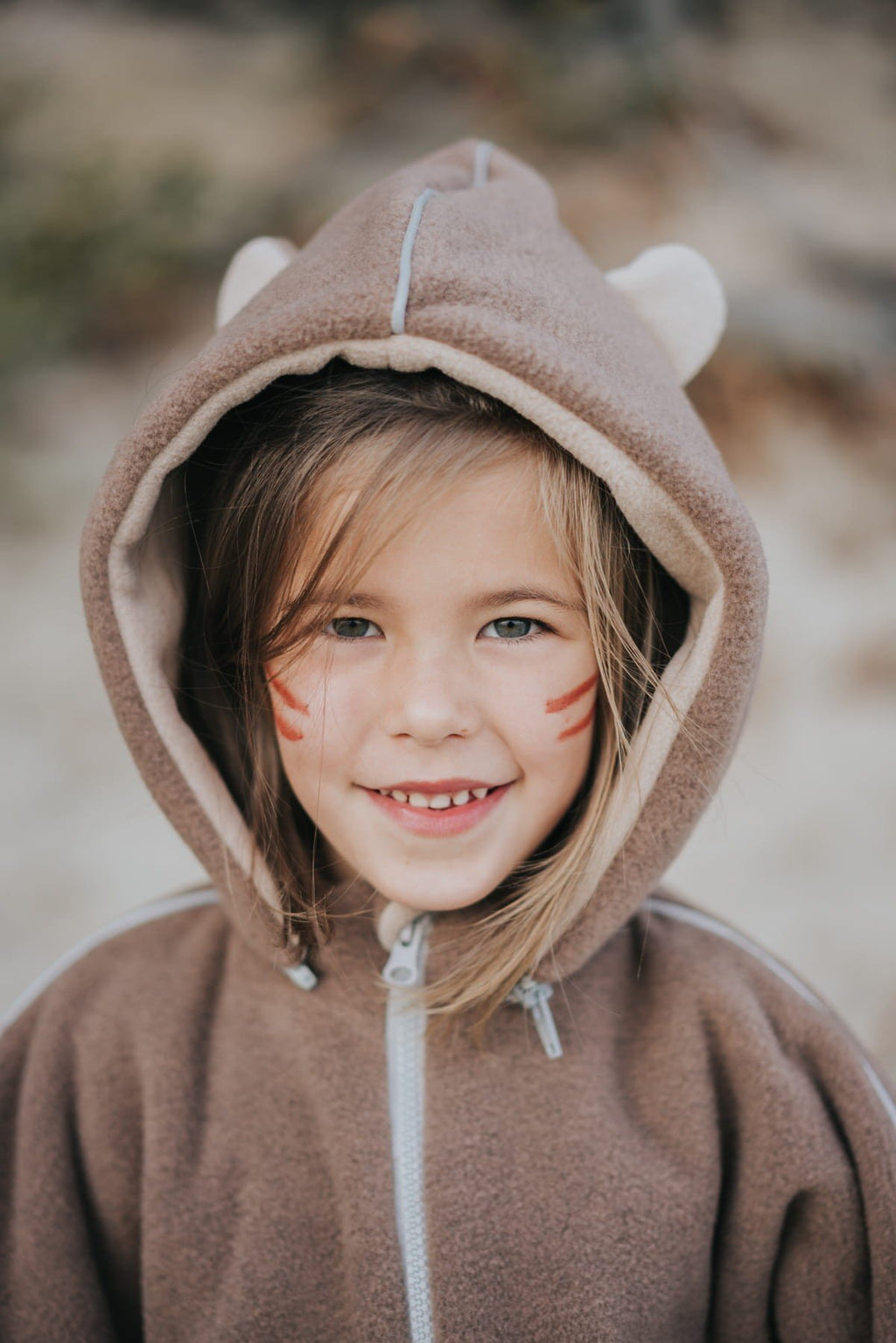 2. Close-up of girl in brown Patulove car poncho with bear ears, smiling outdoors