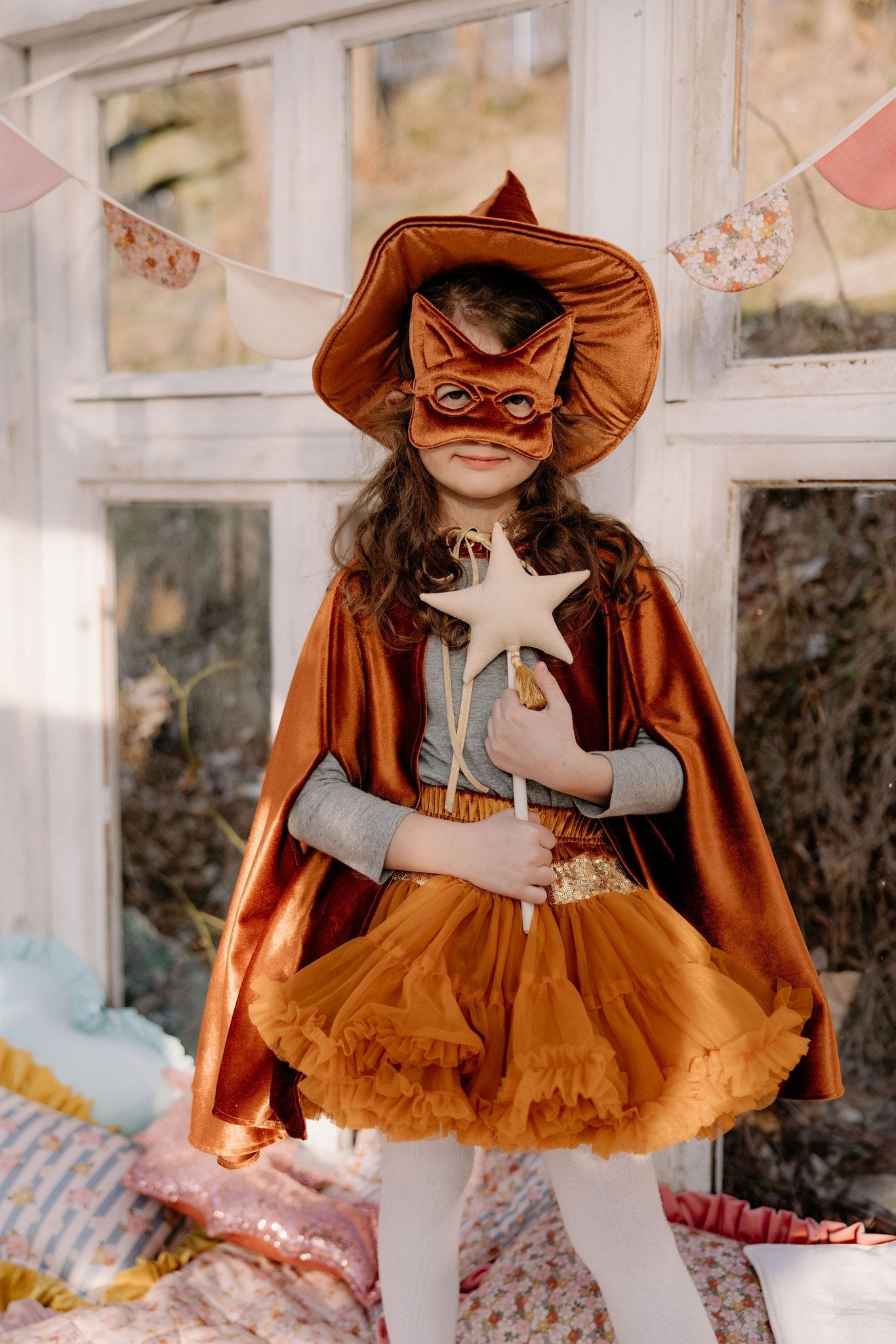 1. Girl wearing ginger cat mask and matching cape with star wand in bright room setting