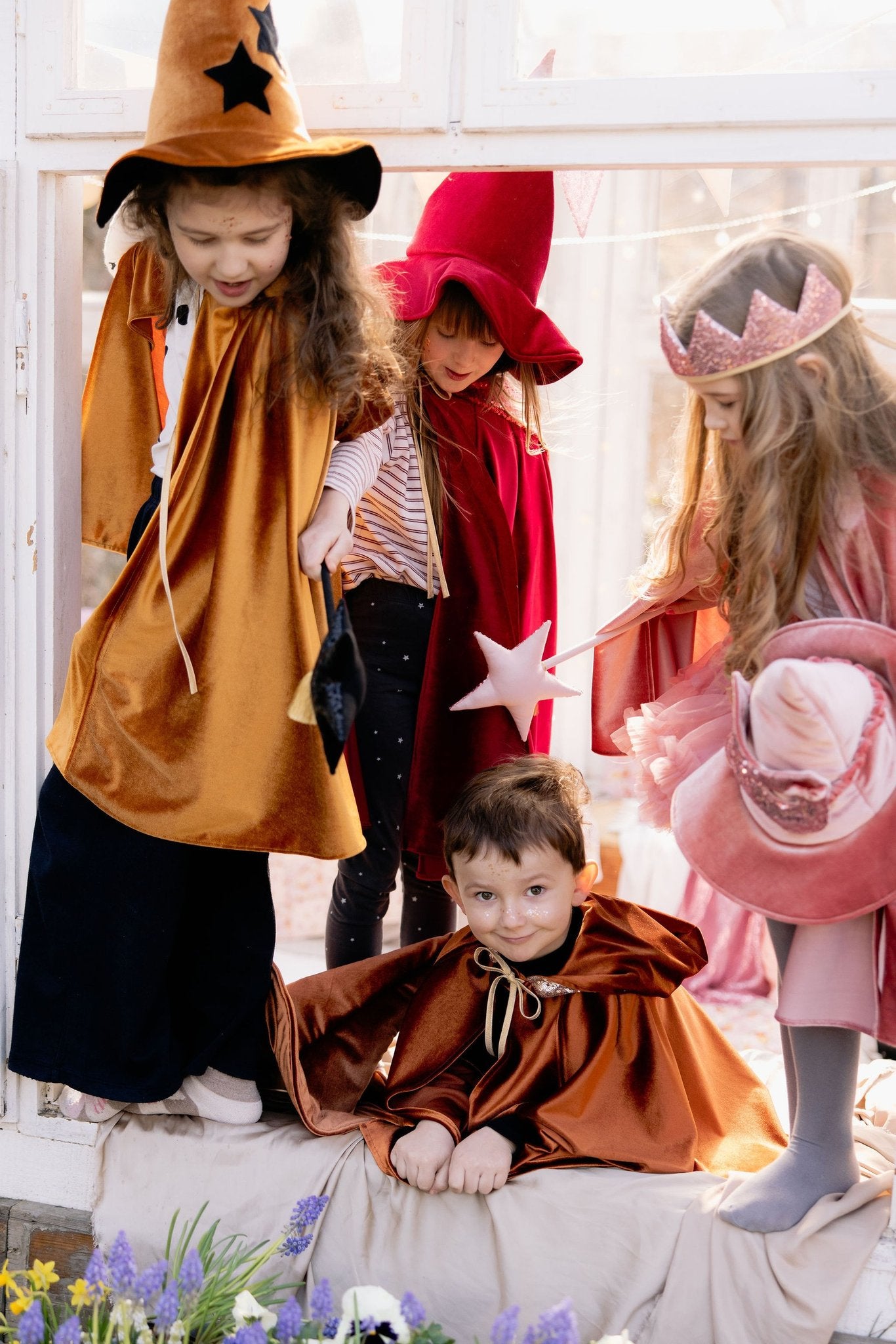 1. Children in costume, one wearing pink sequin cat mask, playing near a window