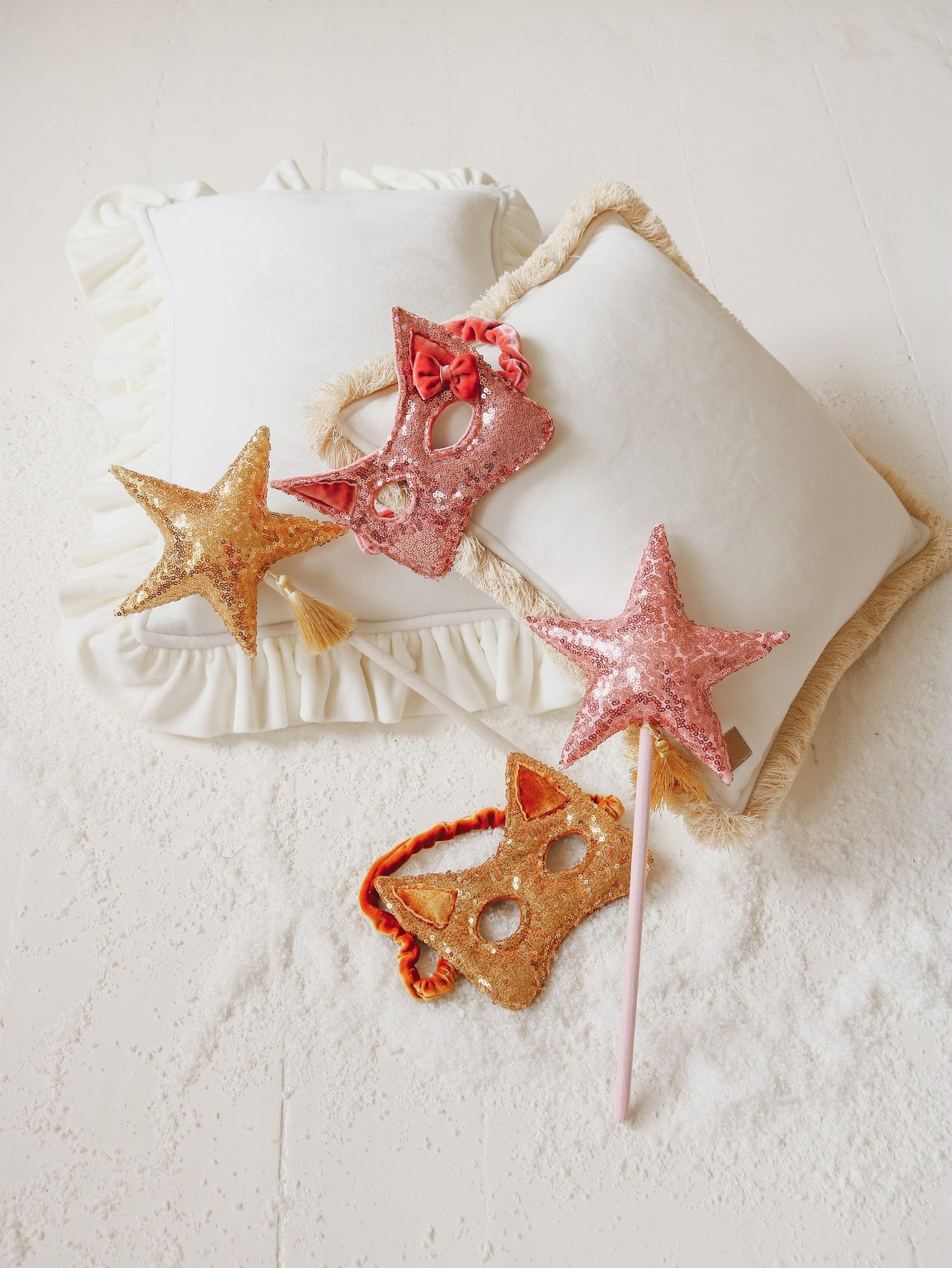 4. Flat lay of pink and gold sequin cat masks with star wands on white pillows