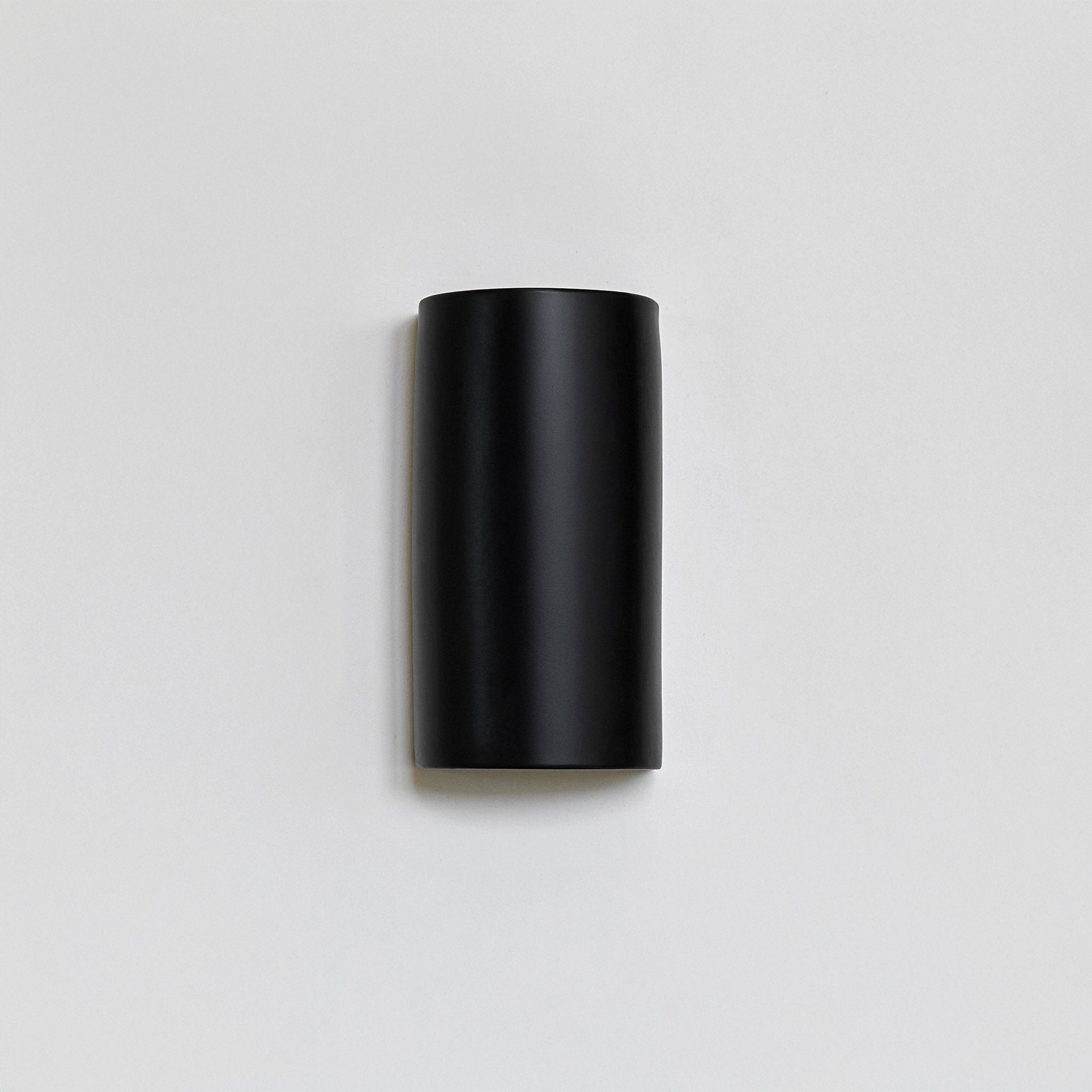 2. Black ceramic wall light by Ora on a plain background, unlit