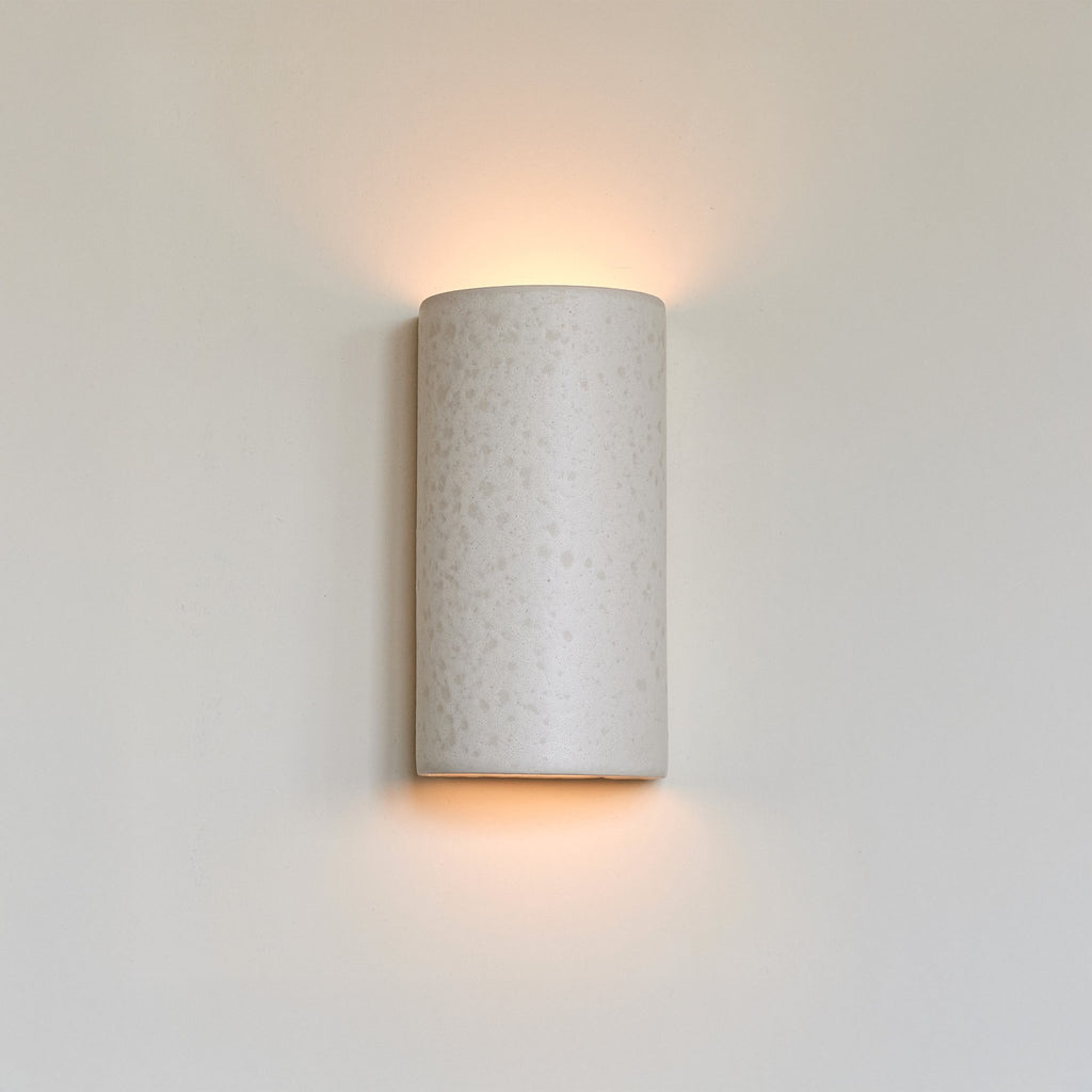 1. Ceramic wall light in raw white with warm glow on plain wall