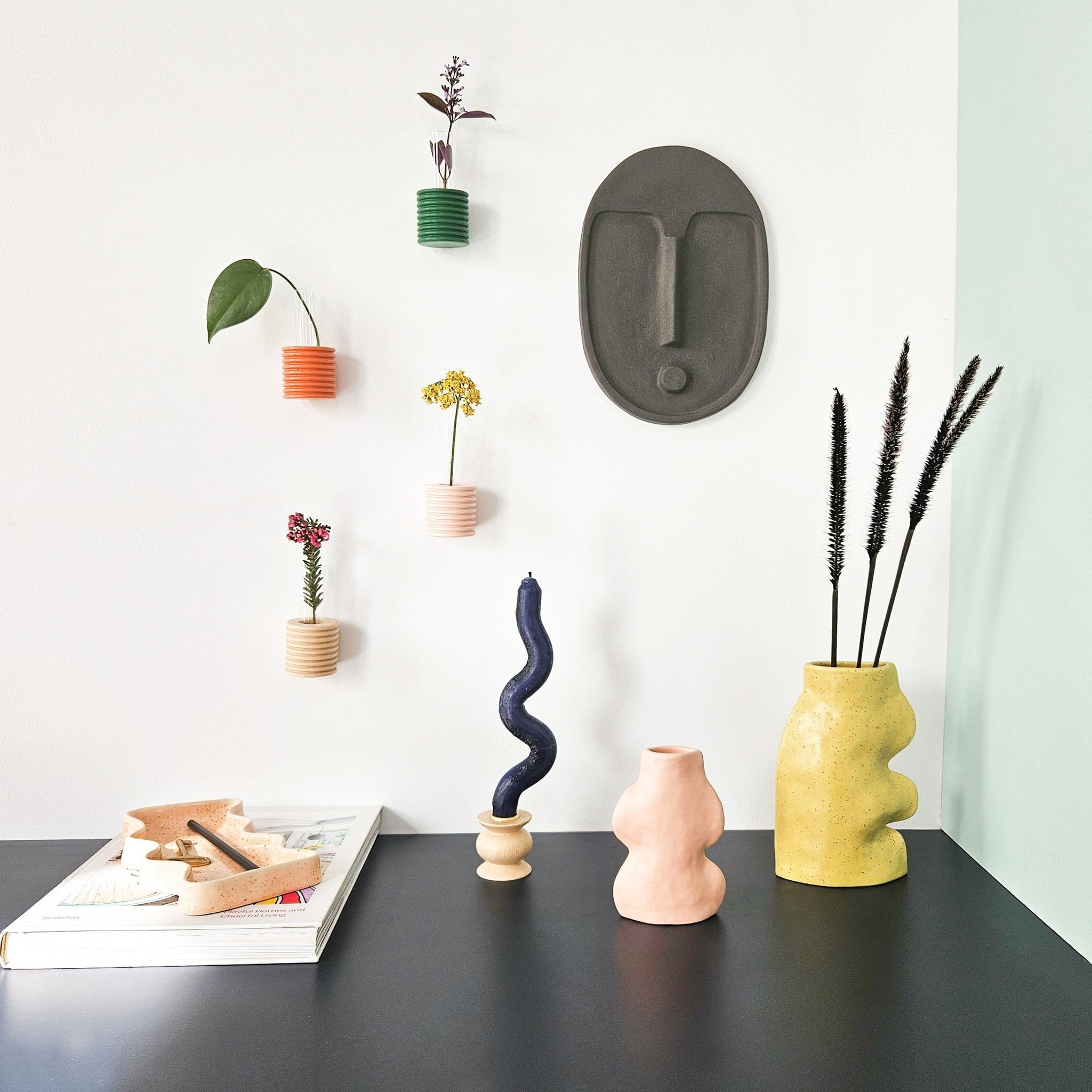 6. Anthracite grey ceramic wall mask by 5mm Paper, featured in a creative wall display with colorful vases