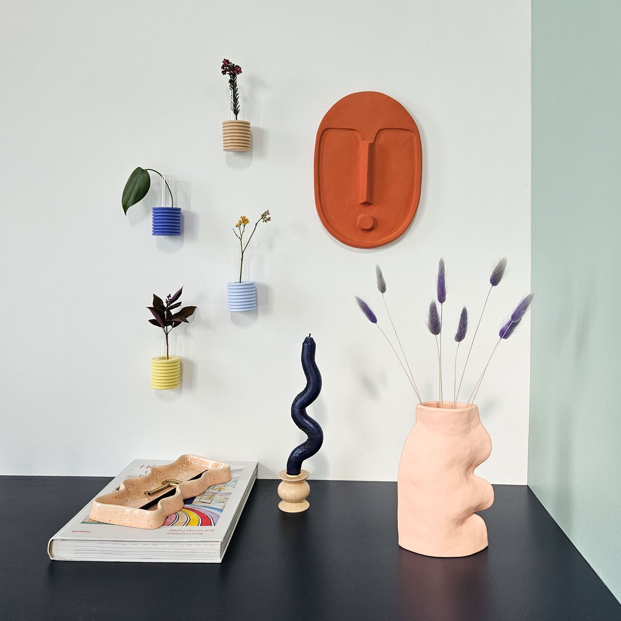1. Ceramic wall mask in terracotta orange by 5mm Paper, styled in a modern living space with decorative elements