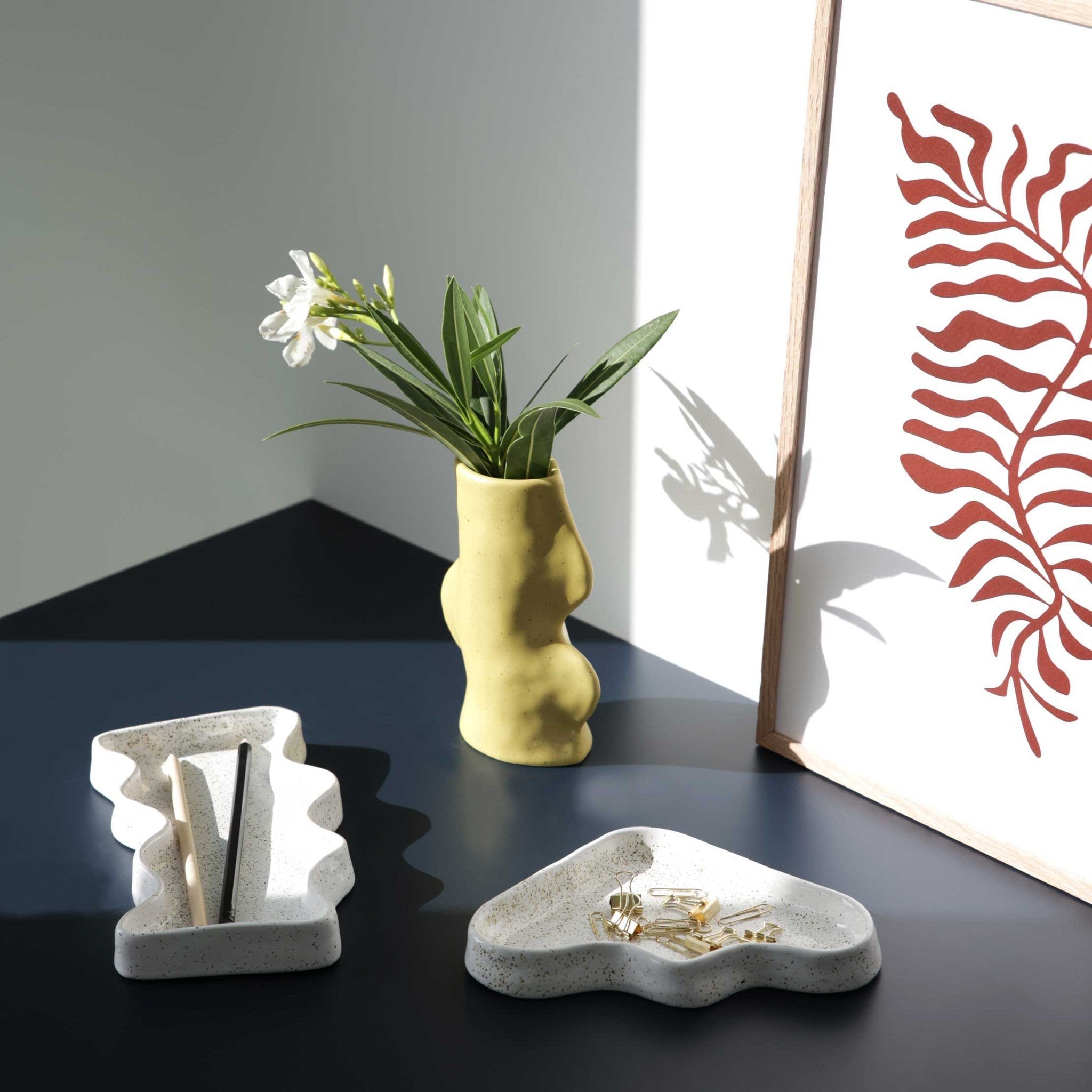 2. Ceramic Wave Tray by 5mm Paper in white, styled with a yellow vase and artwork on a desk